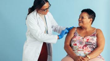 Woman sitting in a chair getting a vaccine from a healthcare professional